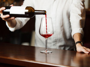 How a sommelier pours red wine into a long stemmed glass